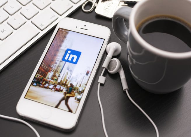 Smartphone, café y audífonos en un escritorio.