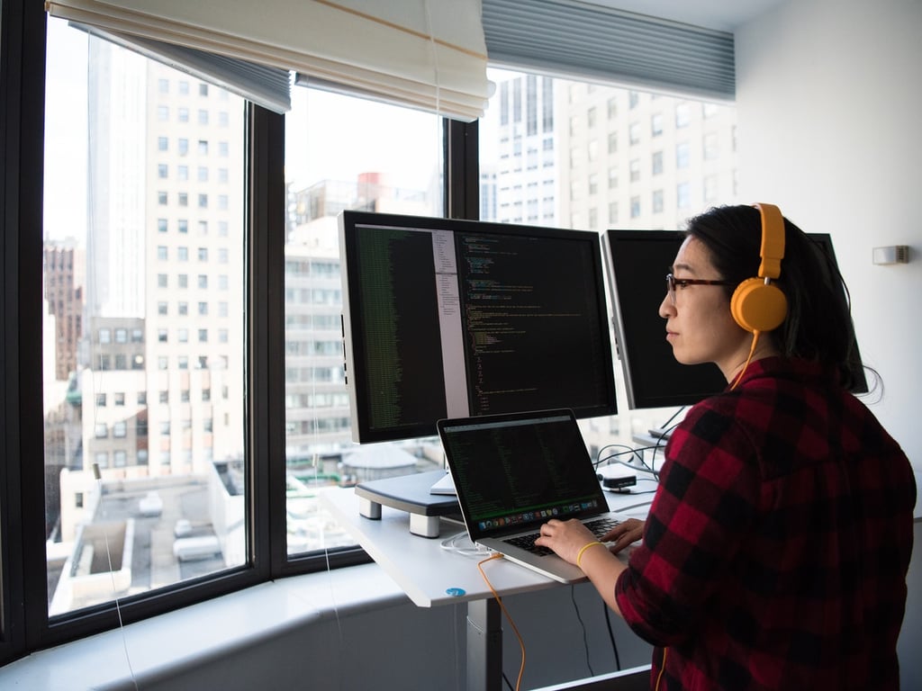mujer frente a un computador y diversas pantallas.
